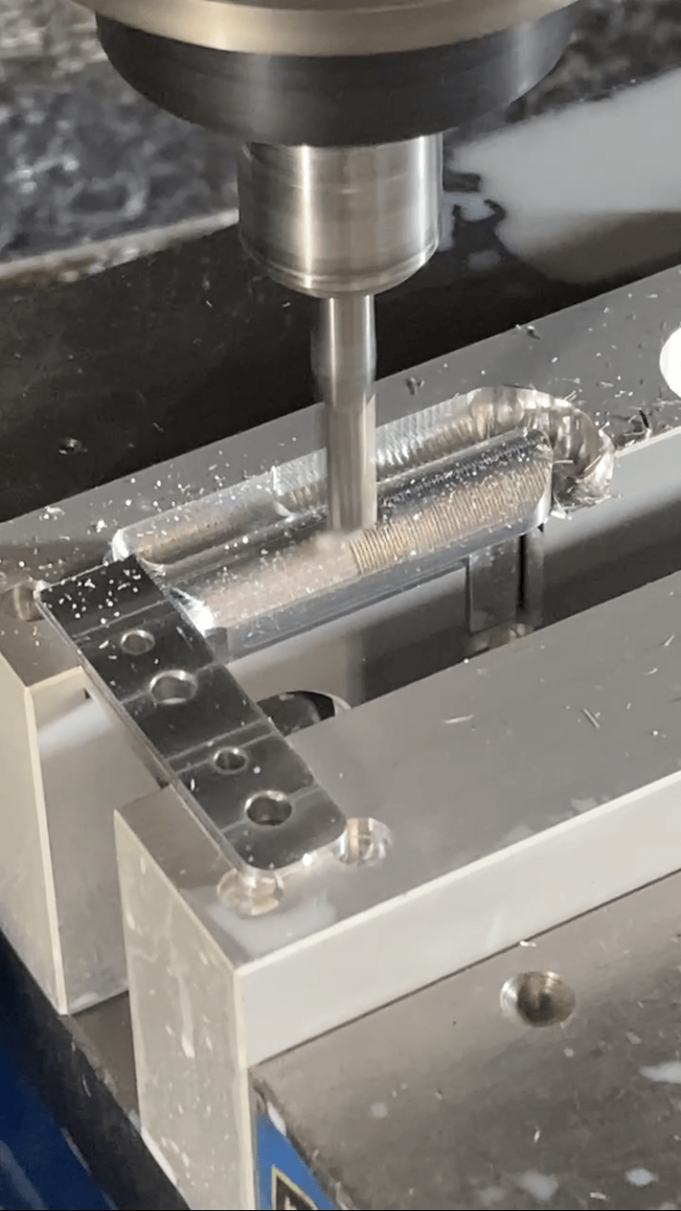 A milling machine cutting precise grooves into an aluminum workpiece, showcasing metal shavings and coolant, illustrating machining processes.